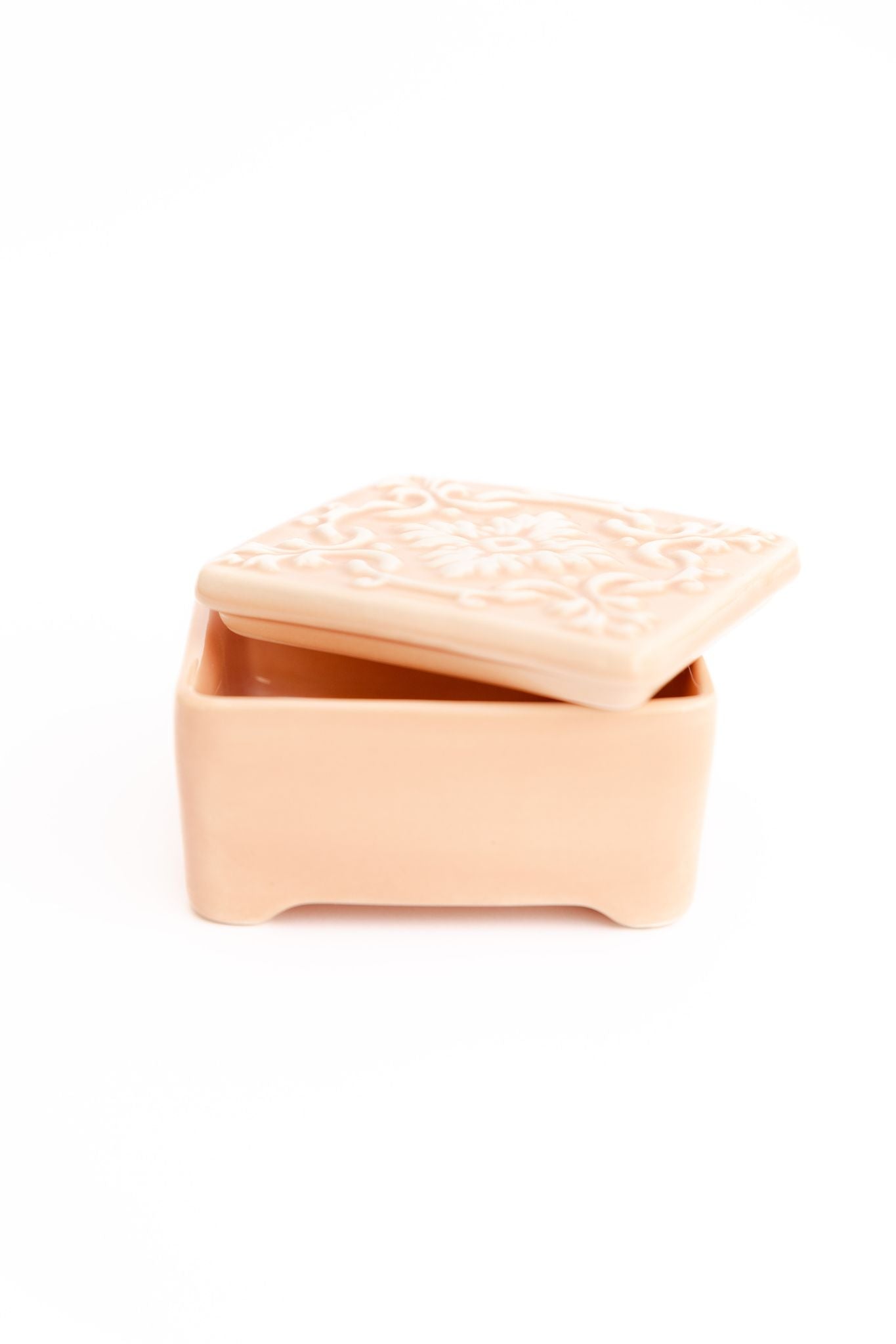 Caixa de joias ALMA em cerâmica rosa nude com tampa entreaberta, destacando o relevo floral artesanal e o tom suave da peça.