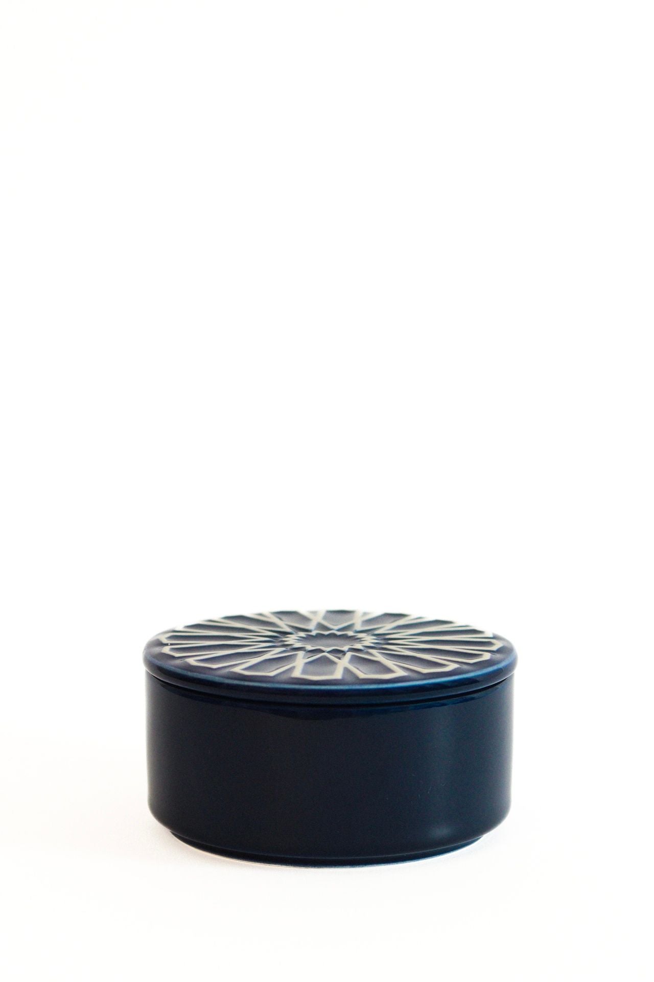 Caixa de joias circular CARISMA em azul escuro, com tampa decorada com motivos geométricos em relevo, ideal para organização e decoração.
