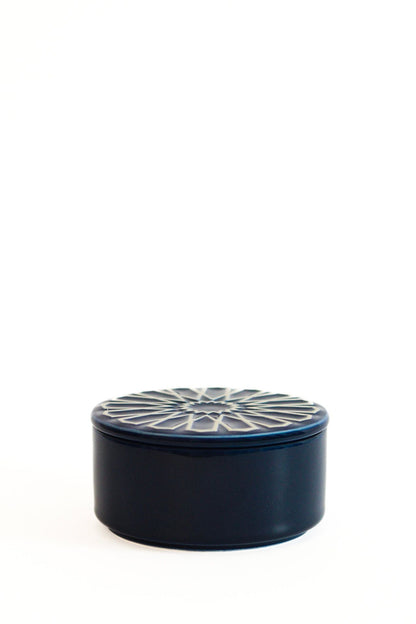 Caixa de joias circular CARISMA em azul escuro, com tampa decorada com motivos geométricos em relevo, ideal para organização e decoração.