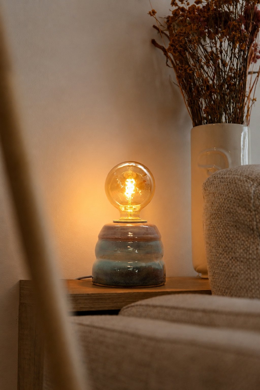 Ambientes de interior com candeeiro Aurora em mesa de apoio junto a elementos decorativos naturais.