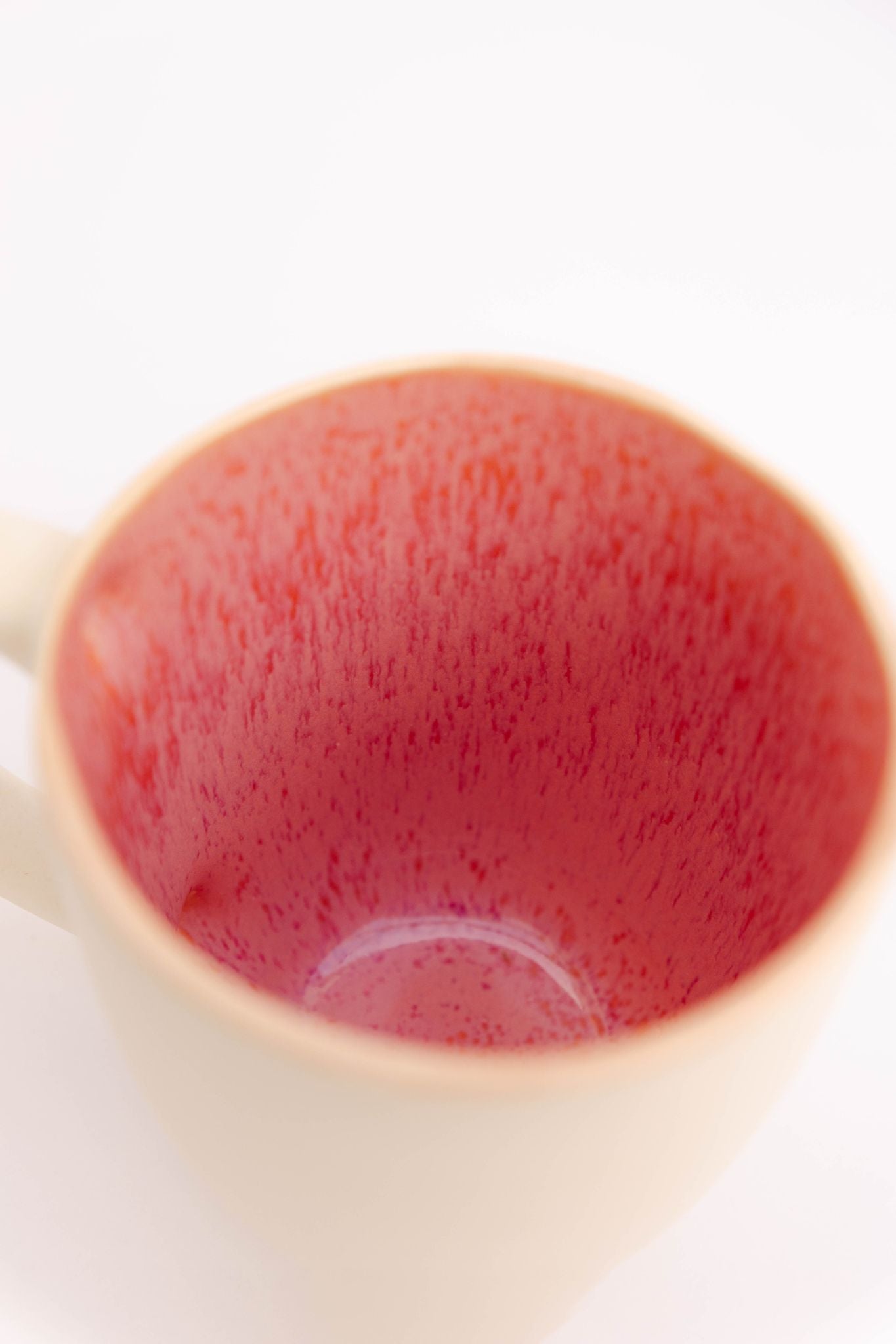 Close-up do interior rosa vibrante da caneca CORAL, realçando a textura pontilhada e orgânica do esmalte cerâmico feito à mão.