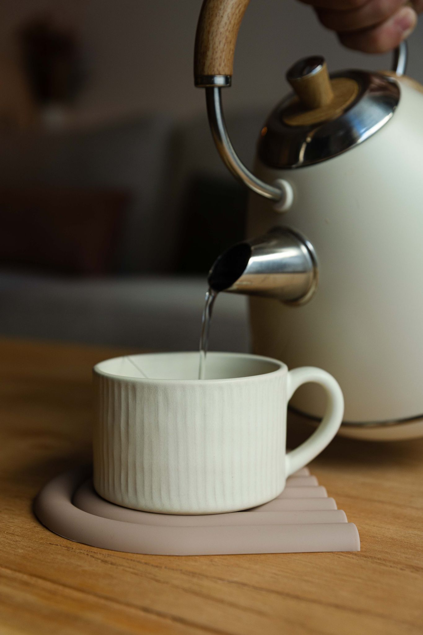 Momento de serviço de chá na caneca PLENO bege, com água a ser vertida de uma chaleira para uma experiência de conforto em casa.