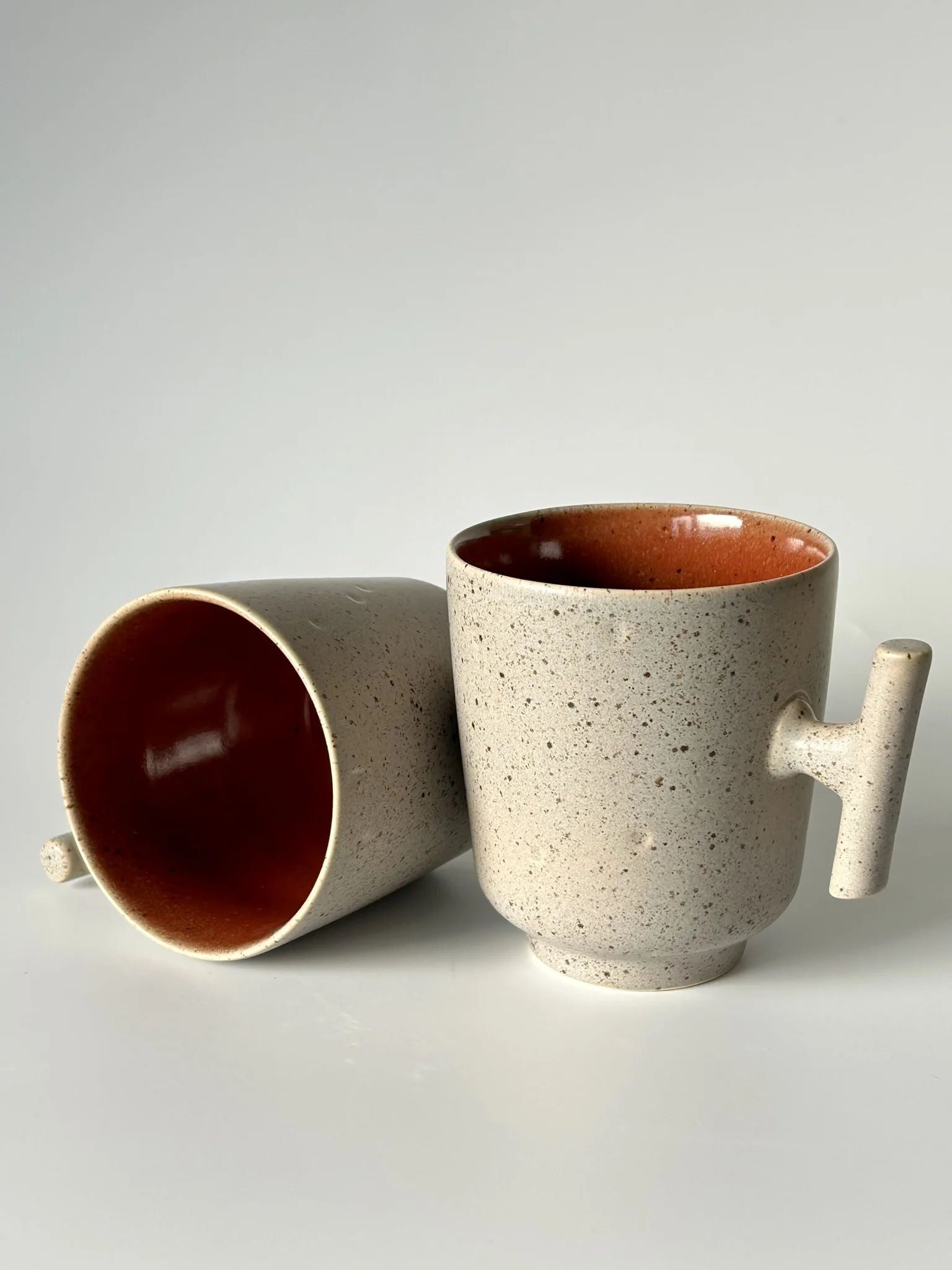 Vista lateral e superior da caneca TERRA 420ml, evidenciando a profundidade do tom vermelho e a robustez da cerâmica artesanal.