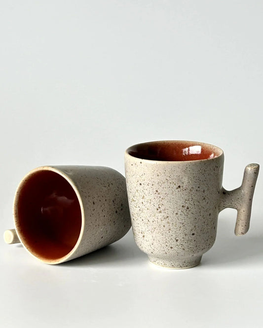 Detalhe dos copos expresso TERRA 80ml, realçando a textura pontilhada do exterior e o brilho do vidrado vermelho quartzo no interior.