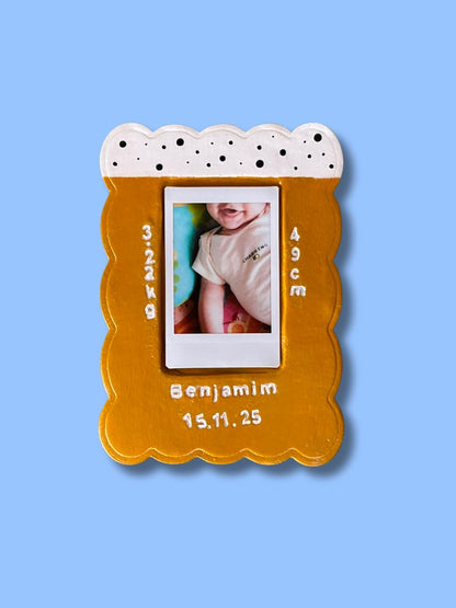 Moldura personalizada em cerâmica fria com fotografia de bebé e dados de nascimento, pintada à mão em tons de mostarda e branco.