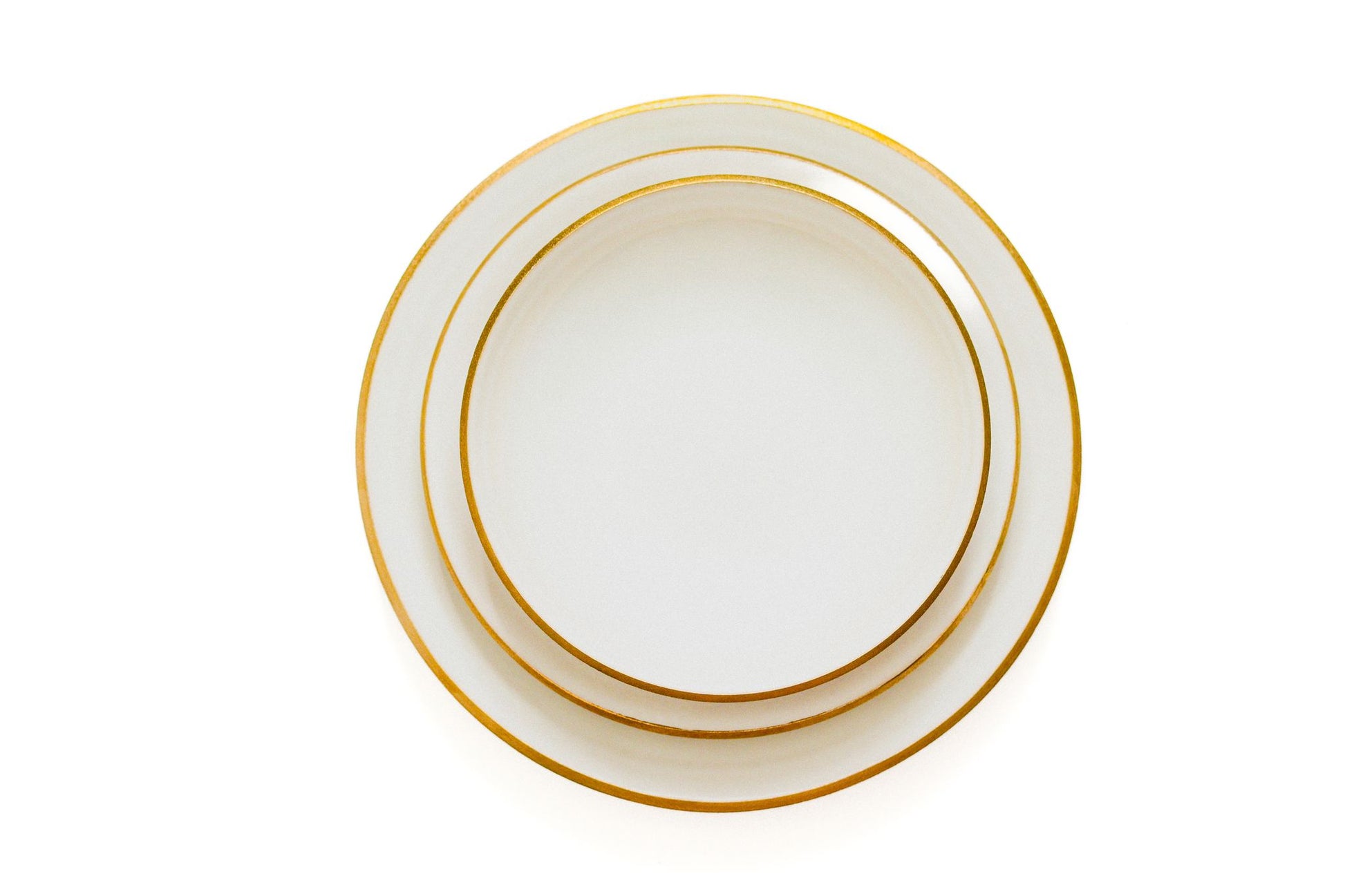Vista superior do conjunto de pratos AURA (Jantar, Sopa e Sobremesa) empilhados, destacando a harmonia dos tamanhos e o elegante bordo dourado.